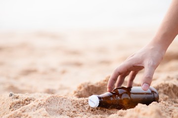 hand keeping bottle on the beach.
