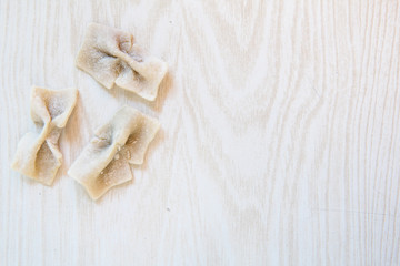 Home made pasta farfalle on the light table. Top view