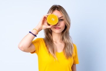 Teenager Russian girl holding an orange isolated on blue background