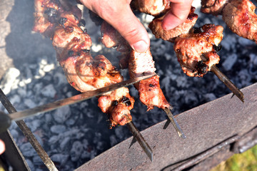 Cooking meat on the grill. Fried food over charcoal. Barbecue weekend. Meat languor at low temperature with smoke from logs. Grill in the open air
