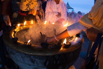 Buddhist woman offering incense and candles burning at the Buddhist monastery altar on the top of...