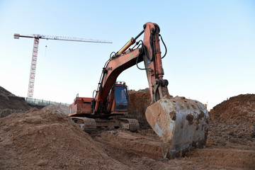 Excavator during earthmoving at construction site. Backhoe digg ground at construction site for the construction of the road and laying sewer pipes district heating. Earth-moving heavy equipment