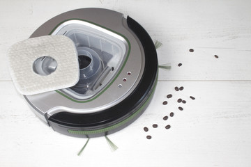 Automatyczny odkurzacz na białych panelach podłogowych, który sprząta ziarna kawy i inne zanieczyszczenia wymagające codziennego czyszczenia.

 - obrazy, fototapety, plakaty