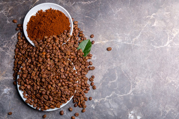 Roasted coffee beans and ground coffee on a marble table
