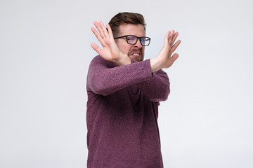 Handsome caucasian man making stop sign, refusing to participate in party.