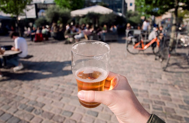 Beer glass in hand of lonely person, walking on city street. Social distancing concept