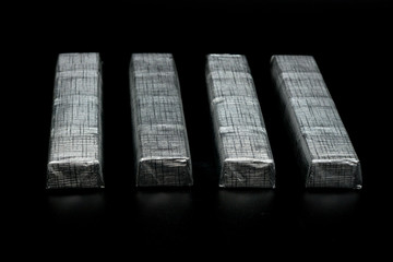 parallel chocolate bars in silver packaging on black background
