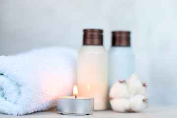 Obraz na płótnie Canvas shower gel and body lotion with a towel and a candle on a light background, the idea of a Spa, hotel.