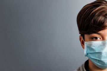 Child with medical mask showing half the face on grey background. Concept of coronavirus quarantine or covid-19