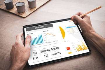 Tablette numérique tenue en main par un homme au travail avec une présentation d'affaires avec...