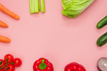 Flat lay from colored vegetables on a pink background. Space for text.