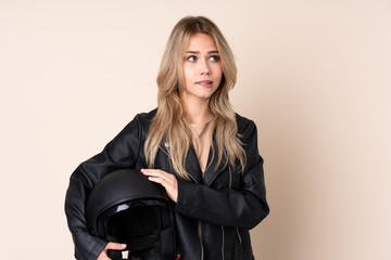 Russian girl with a motorcycle helmet isolated on beige background with confuse face expression