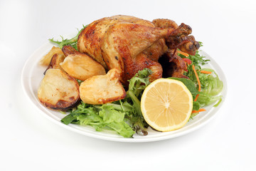 Whole roasted grilled chicken poultry bird with baked potato vegetable salad tomato lemon on white background
