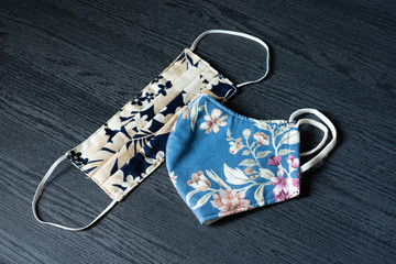 Disposable surgical face mask made from cotton fabric in tropical pattern design. for cover mouth and nose,  protection against flu, corona virus(COVID-19) and other diseases on black background.