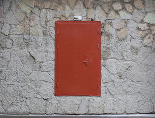 Metal brown door with a high threshold in the wall, lined with artificial stone