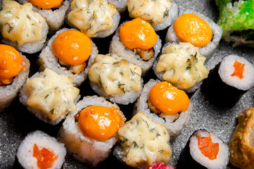 A large set of various rolls and sushi. Hats from the sauce. Baked rolls. Close-up