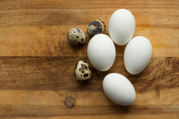 chicken and quail eggs are laid on a wooden cutting Board