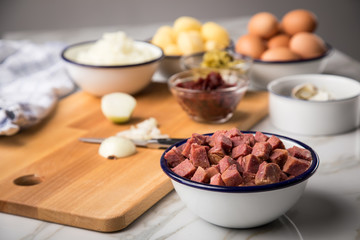 Zutaten  für Norddeutscher Hamburger Labskaus mit Rindfleisch Corned Beef, Rote Beete, Kartoffeln, Saure Gurken, Zwiebeln, Ei und Rollmops auf Marmor Arbeitsfläche