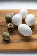 chicken and quail eggs are laid on a wooden cutting Board