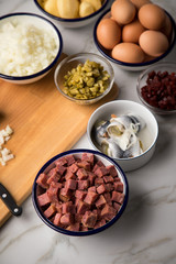 Zutaten  für Norddeutscher Hamburger Labskaus mit Rindfleisch Corned Beef, Rote Beete, Kartoffeln, Saure Gurken, Zwiebeln, Ei und Rollmops auf Marmor Arbeitsfläche