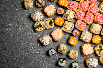 A large set of various rolls and sushi. Hats from the sauce. Baked rolls. Gray background