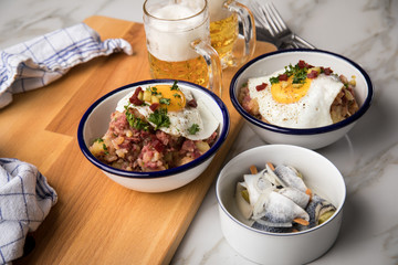 Norddeutscher Hamburger Labskaus mit Rindfleisch Corned Beef, Rote Beete, Kartoffeln, Saure Gurken, Spiegelei, Rollmops und Bier auf Marmor