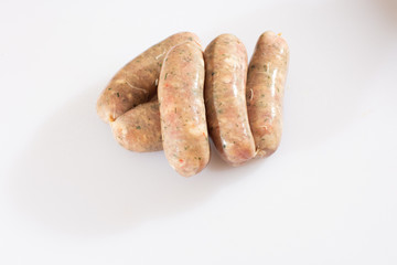 Raw pork beef sausages on white background. Traditional German homemade sausages. Delicious raw meat for barbecue. Advertising for meat shop and farm. Top view. Space for text