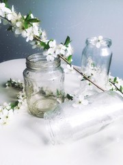 Obraz na płótnie Canvas glass jars with water drops close up with a cherry blossom branch