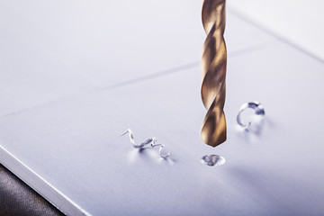 metal drill bit make holes in aluminum billet on industrial drilling machine with shavings. Metal...