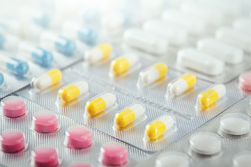 pile of medical pills  in red, blue and yellow colors in  silver plastic packaging