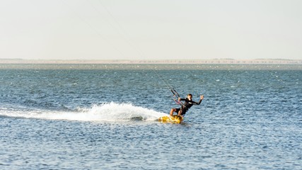 Fototapeta na wymiar Man kitesurfer rides kite splashing at Black Sea coast on sunny day. Blagoveshenskaya. Anapa, Russia.