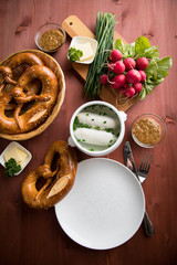 Münchener Weißwurst in Terrine mit bayrischer süßen Senf, Brezel, Radieschen, Schnittlauch und Butter auf Holz Tisch