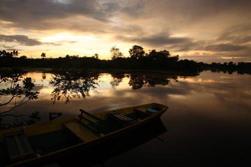 Fototapeta na wymiar Landscape of Amazon jungle river with floating boat during sunrise in Brazil