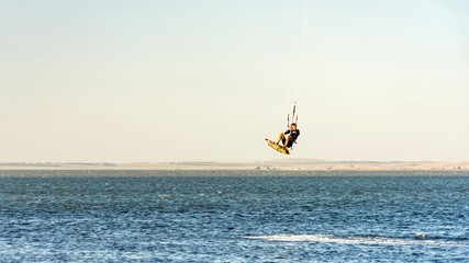 Man kitesurfer rides kite jumping. Black Sea coast on sunny day. Blagoveshenskaya. Anapa, Russia.