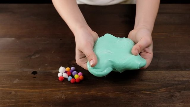 Green slimy toy in the hands of children on a blue background. To make the slime. Copyspace. Flatley.