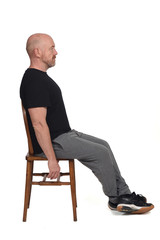 Fototapeta premium Bald man with sportswear sitting on a chair on white background.