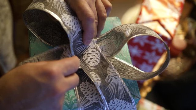POV Hands Wrapping Christmas Tree green gift Box presents. Silver Ribbon bow decorative snowflakes. Isolated closeup.
