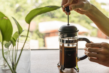 Making coffee with French Press coffee maker. Pressing the plunger of the French press coffee maker...