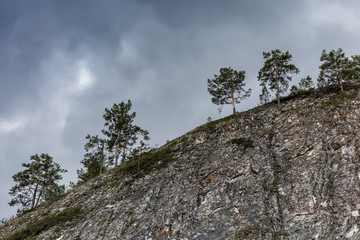 beautiful landscape with green forest and high rocky mountain under dark blue sky. dramatic nature