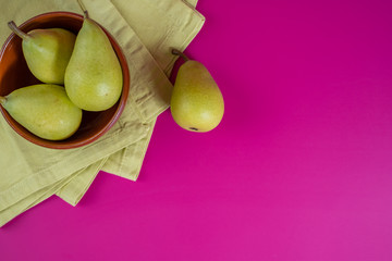 green pears in a bowl on background