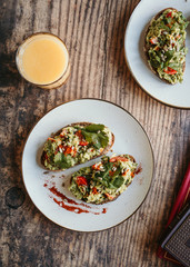 Avocado toasts with tomatoes and glass of orange juice