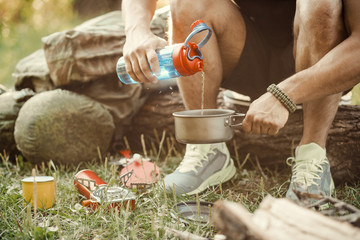 Man traveler hands holding a Cup of tea outdoors. The concept of adventure, travel, tourism and camping. Tourist drinking tea from a mug in the camp