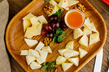 wooden plate with fried cheese, grape and sauce