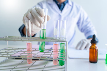 scientists researching in laboratory in white lab coat, gloves analysing, looking at test tubes sample, biotechnology concept