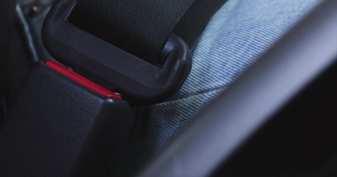 Close up female hand fastening car safety seat belt while sitting inside of vehicle before driving