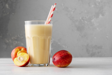 Fresh protein shake with nectarine or peach on a white wooden table. Fresh apricot milkshake. A...