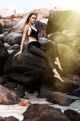 Young sexy woman sitting on the rocks on the beach