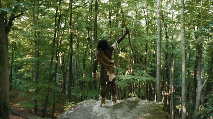 Primitive tribesmen leader of hunter-gatherers feeling pride and freedom on edge of mountain in...