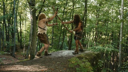 Two persistent angry wild men fighting for tribe leadership on mountain edge in prehistoric competition in jungle forest. Hunter-gatherers of stone-age period.