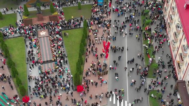 Gomel, Belarus - 05/09/2019: Crowd of people on a city festive street, top view, vertical flight over the roofs of bright city houses